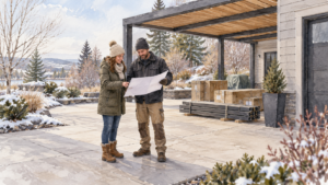 Homeowner and installer reviewing a plan beside a clear patio in winter. Concept visualization · Not a customer installation